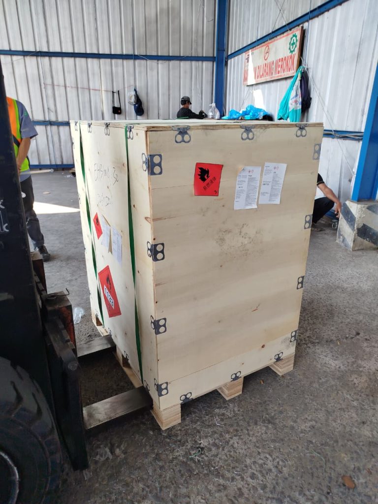 Staf profesional USLOGT memuat peti kargo berisi bahan kimia mudah terbakar (Flammable Liquid) kelas 3 ke dalam kontainer sesuai standar keselamatan.