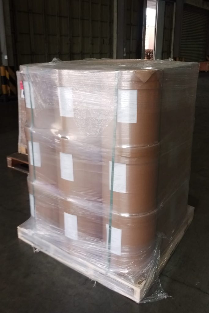 Barel material kimia yang dibungkus plastik pelindung (shrink wrap) tersusun rapi di atas palet kayu dalam fasilitas gudang USLOGT.
